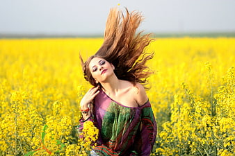 Young woman with flowing hair in yellow flower field