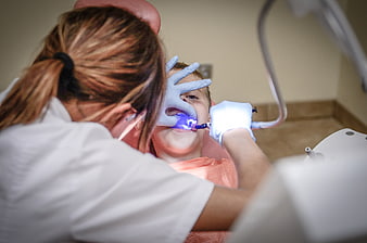 Dentist treating child patient with blue curing light