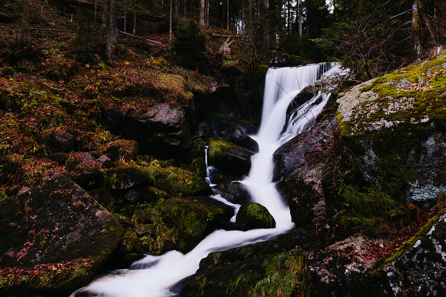 Misty waterfall cascading over mossy rocks in a dark forest