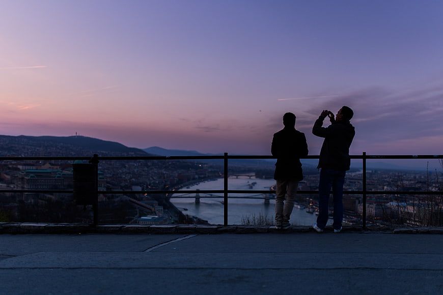 Silhouettes of Two People Watching Sunset Over City River