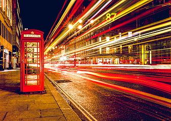 Red London telephone booth with long exposure traffic light trails at night