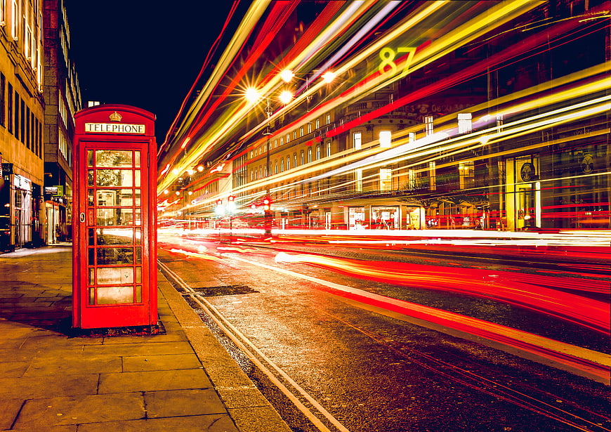 Red London telephone booth with long exposure traffic light trails at night