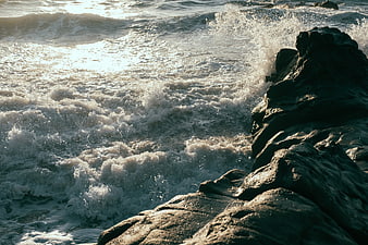 Rough Ocean Waves Crashing Against Dark Rocky Coastline