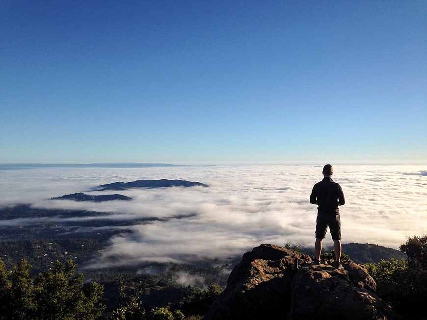 Man standing on rocky peak overlooking sea of clouds