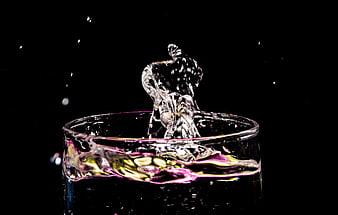 Dynamic water splash in glass with colorful reflections