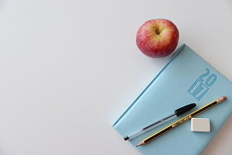 Minimalist school supplies with red apple on white background