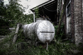 Abandoned metal oil tank in overgrown backyard
