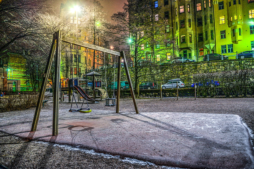 Empty Winter Playground at Night with City Buildings