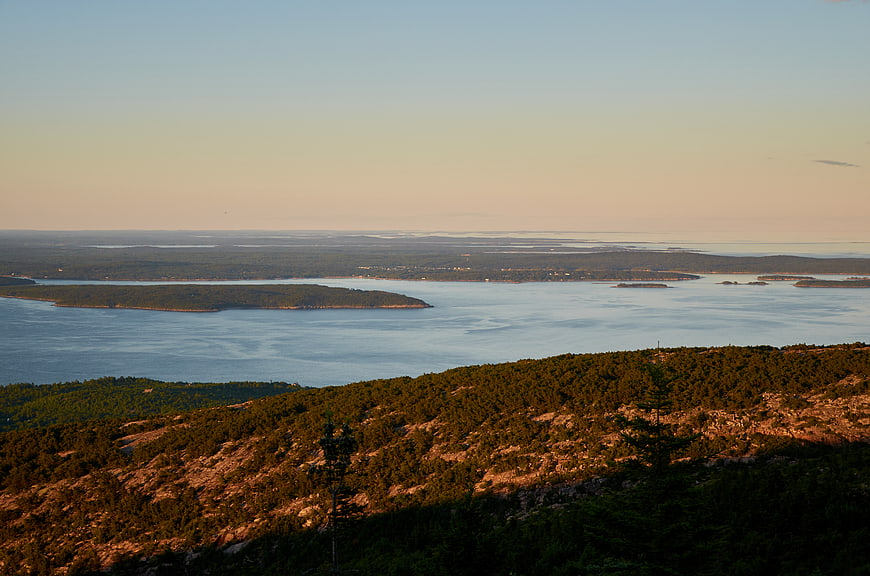 Scenic coastal landscape with rocky hills and calm ocean at sunset