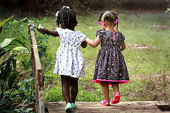 Two young girls walking away on a wooden bridge