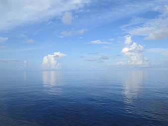 Serene Ocean Horizon with Fluffy White Clouds and Blue Sky