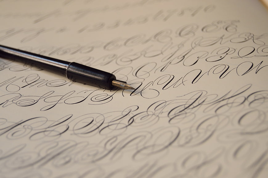 Close-up of calligraphy pen on vintage cursive handwriting