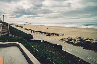 Wide Angle View of Coastal Beach Path with Cyclists and Pier