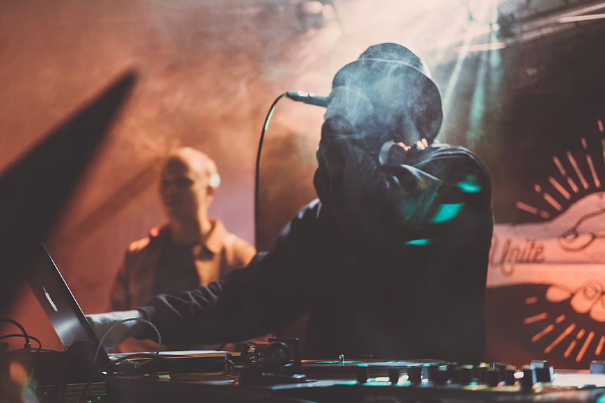DJ performing live with microphone and mixer in dark club
