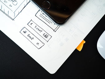 Hand-drawn mobile app wireframe sketch on paper with smartphone