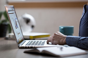 Close-up of person typing on laptop in office workspace