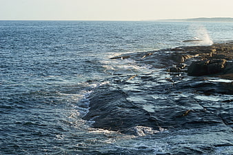 Waves crashing on rocky coastline at golden hour