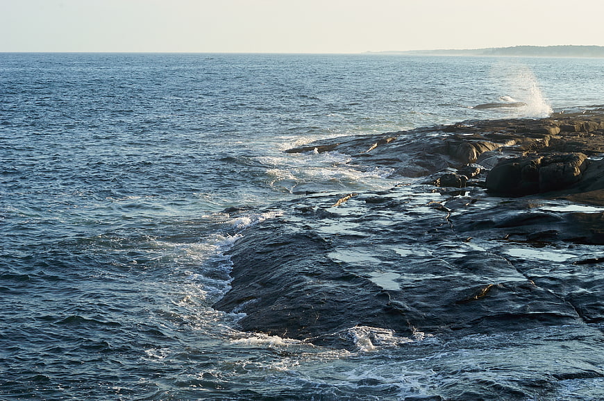 Waves crashing on rocky coastline at golden hour