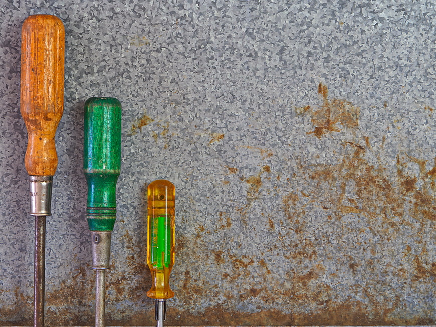 Vintage screwdrivers on rusty metal background with copyspace