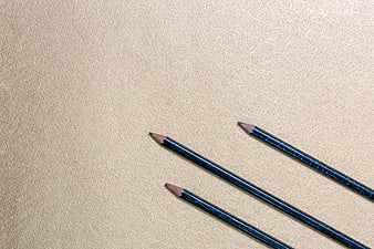 Blue pencils on textured beige background with copy space