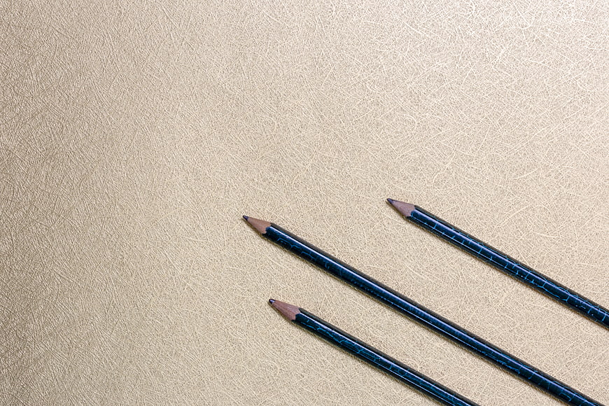 Blue pencils on textured beige background with copy space