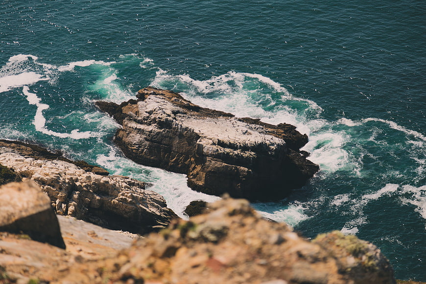 Aerial View of Turquoise Waves Crashing Against Rocky Coastline