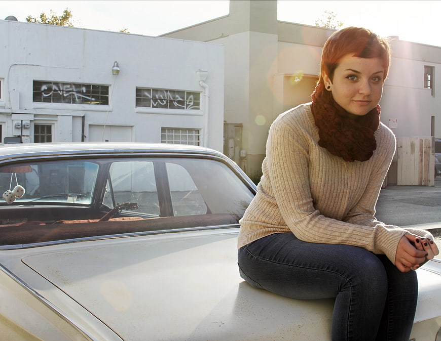 Woman with red hair sitting on vintage car hood