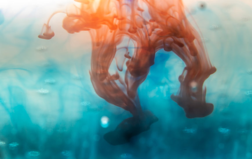 Abstract orange ink swirling in blue water background