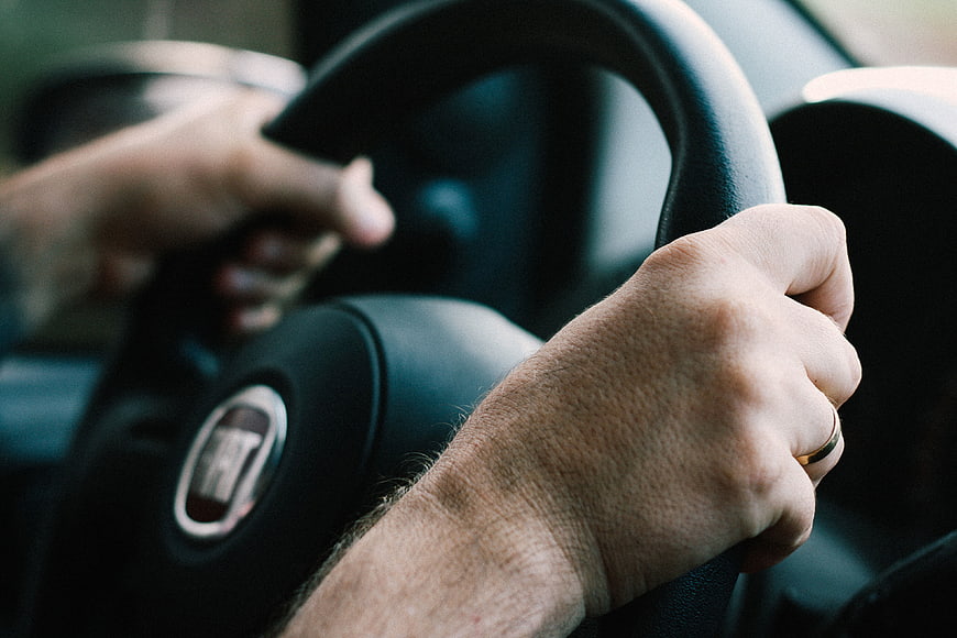 Close-up of male hands gripping a car steering wheel