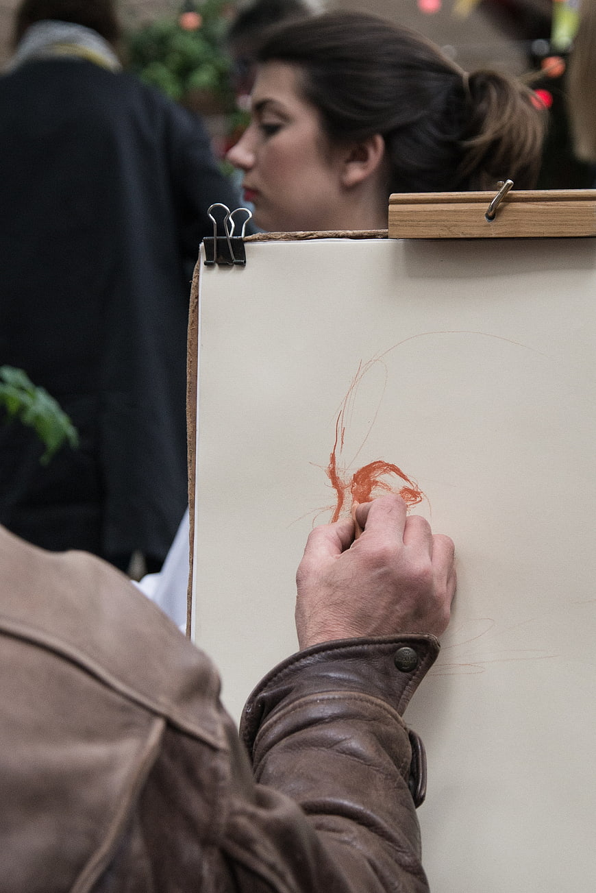 Close-up of artist sketching with red chalk on paper