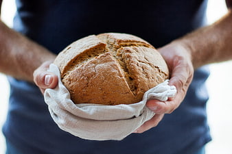 Man holding fresh rustic sourdough bread loaf