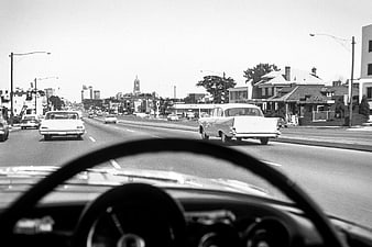 Vintage black and white photo of driving down a city street in the 1950s
