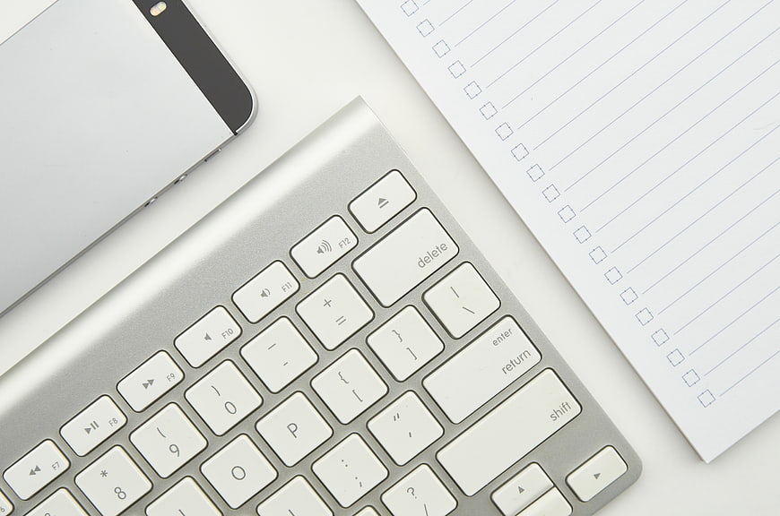 Minimalist Workspace with Keyboard, Smartphone, and Checklist Notepad