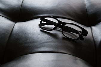 Black eyeglasses resting on a leather sofa