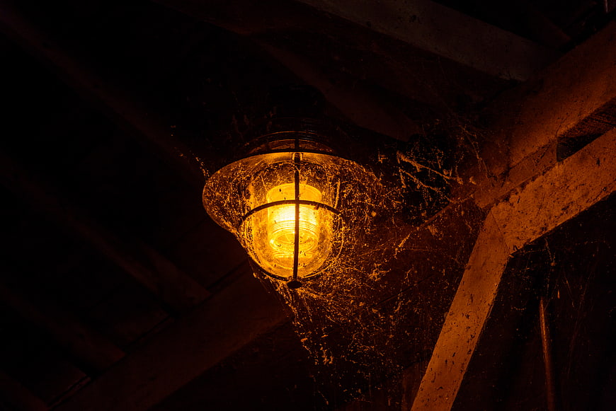 Dusty vintage lantern with spider webs in dark attic