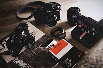 Vintage and modern cameras with film on wooden table