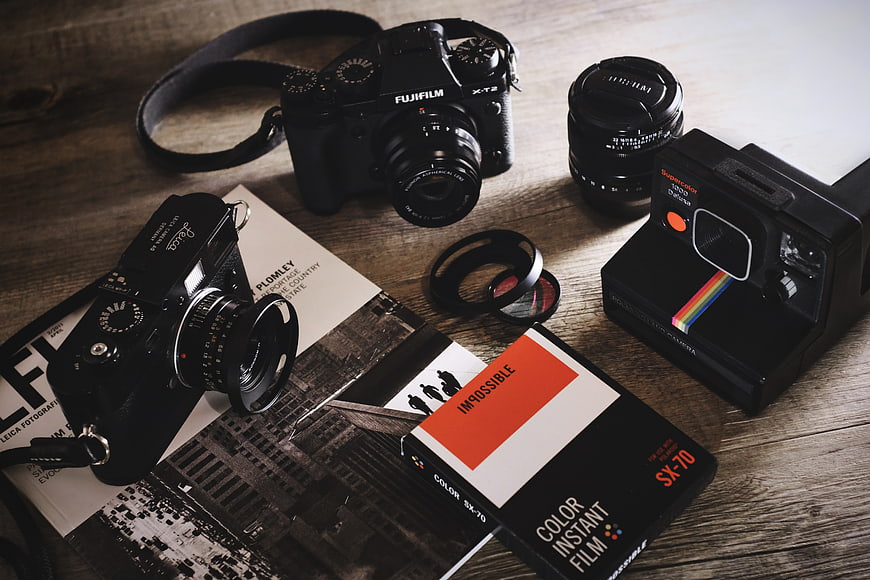 Vintage and modern cameras with film on wooden table