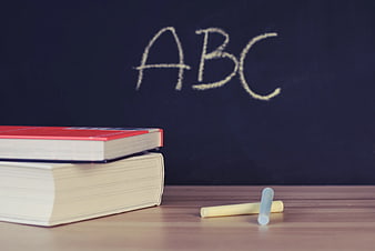 ABC written on chalkboard with books and chalk