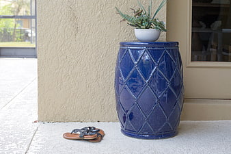 Blue ceramic garden stool with plant and sandals on patio