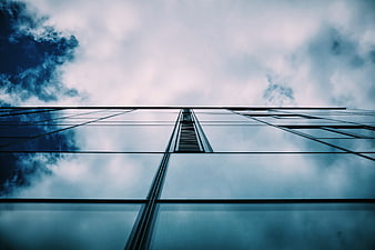 Low angle view of modern glass skyscraper reflecting blue sky