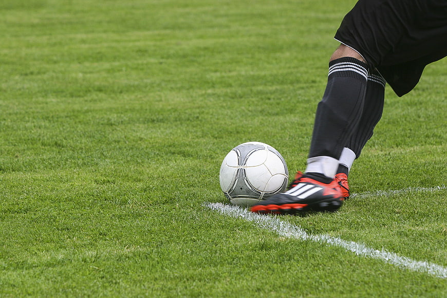 Soccer Player Kicking Ball on Green Grass Field