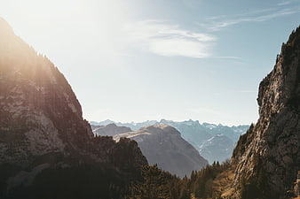 Sunlit Mountain Valley with Distant Peaks and Pine Forest