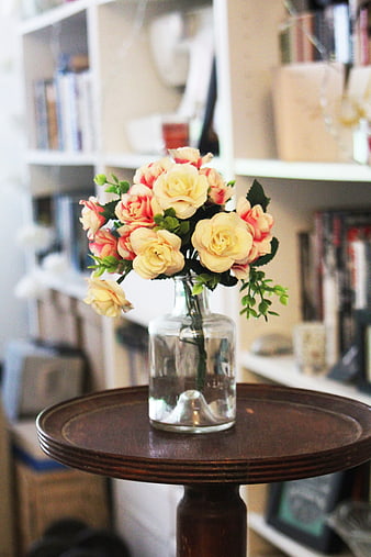 Yellow and pink roses in a glass vase on a wooden table