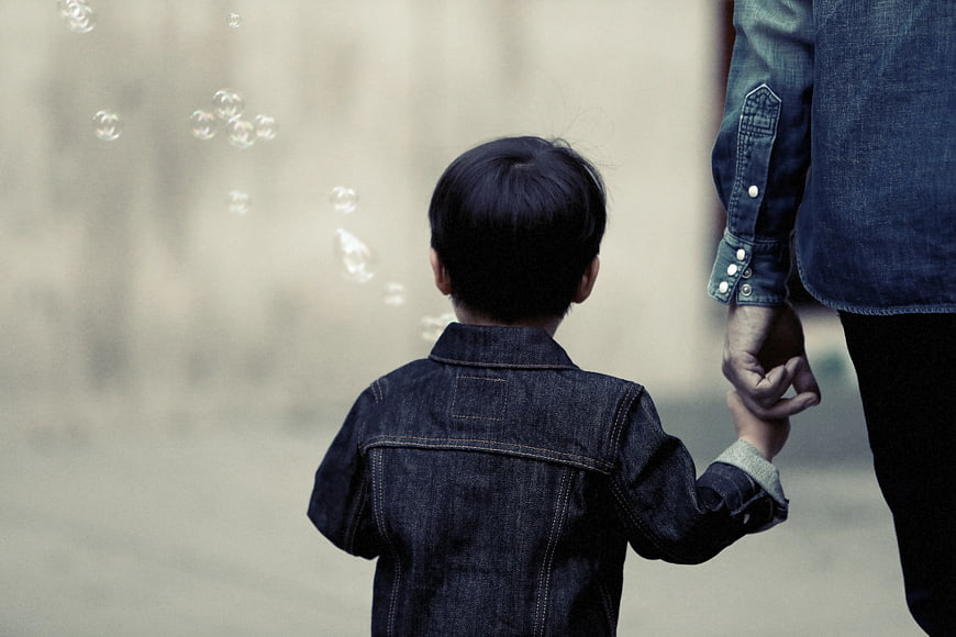 Child holding adult hand watching bubbles