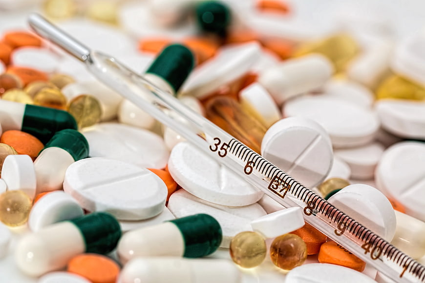 Glass Thermometer on Pile of Colorful Medical Pills