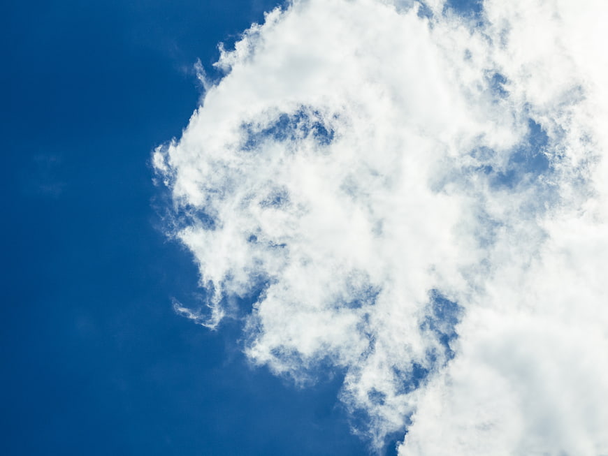 Fluffy white clouds against a deep blue sky background