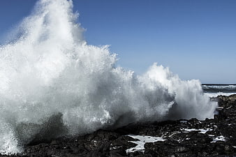 Powerful Ocean Wave Crashing Against Dark Rocky Coastline
