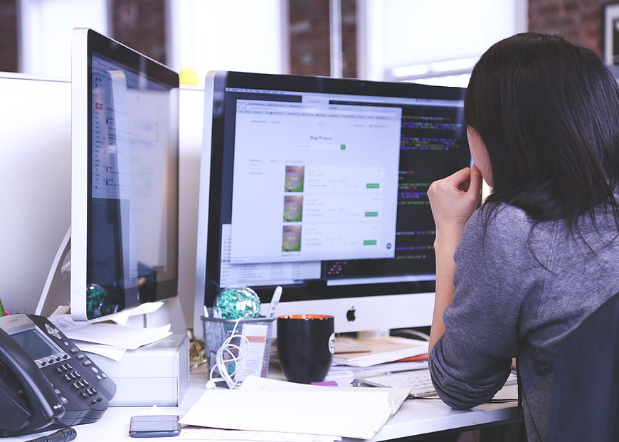 Woman working at dual monitor computer desk