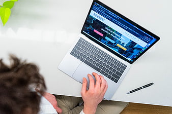 Overhead view of person using laptop on white desk
