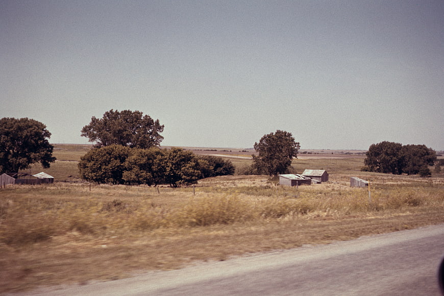 Vintage rural landscape with barns and trees from moving car